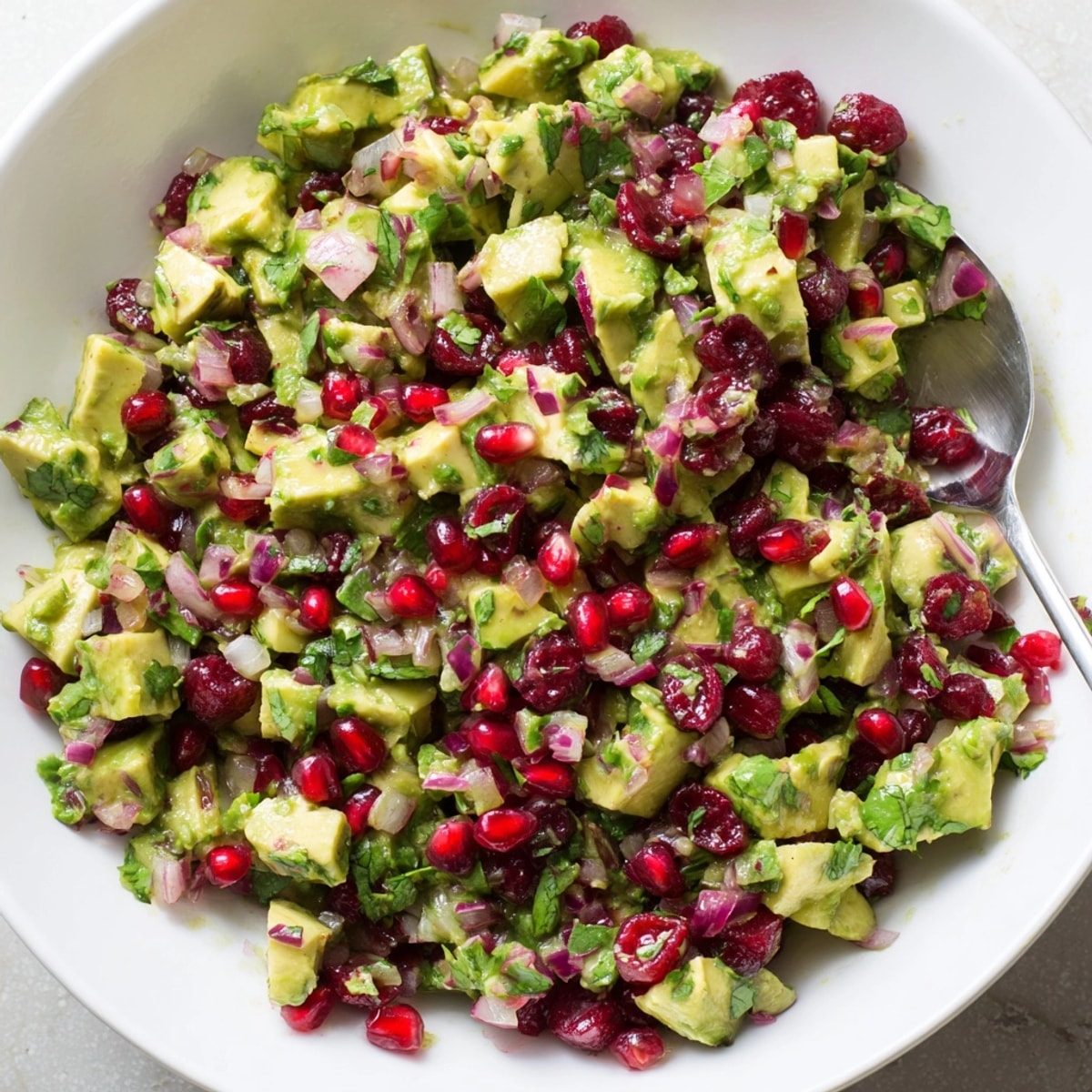 Close-up of vibrant Cranberry Jalapeño Avocado Salsa, ready to be scooped with tortilla chips.