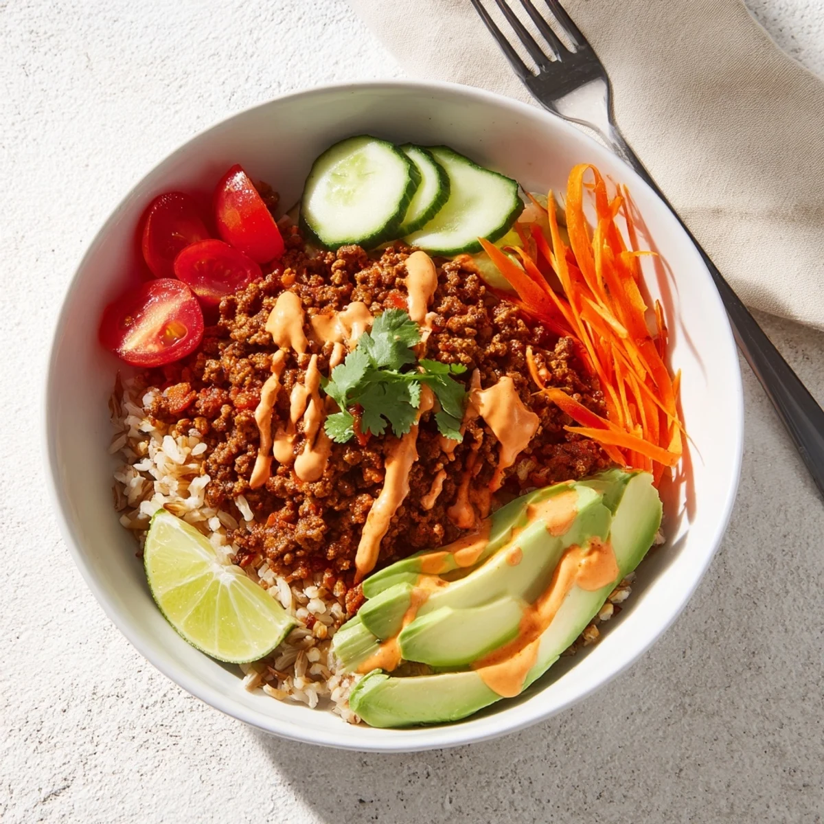 Savory plant-based meat bowl garnished with cilantro, avocado, and spicy mayo sauce.  