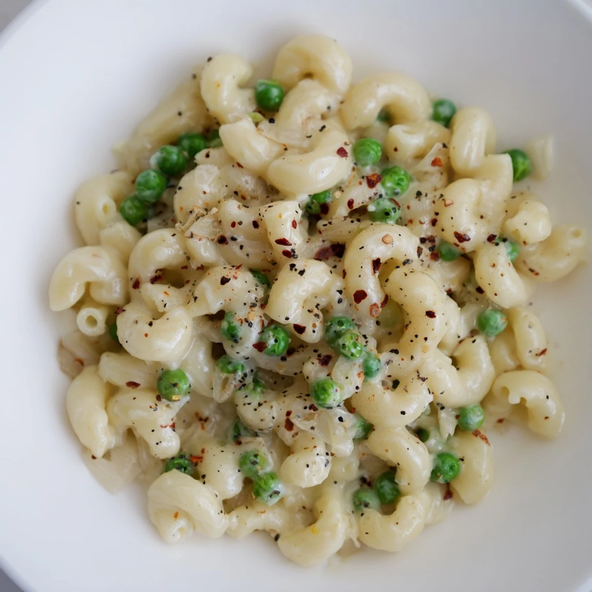 Warm, creamy macaroni and peas with parmesan cheese, ready for a comforting bite.