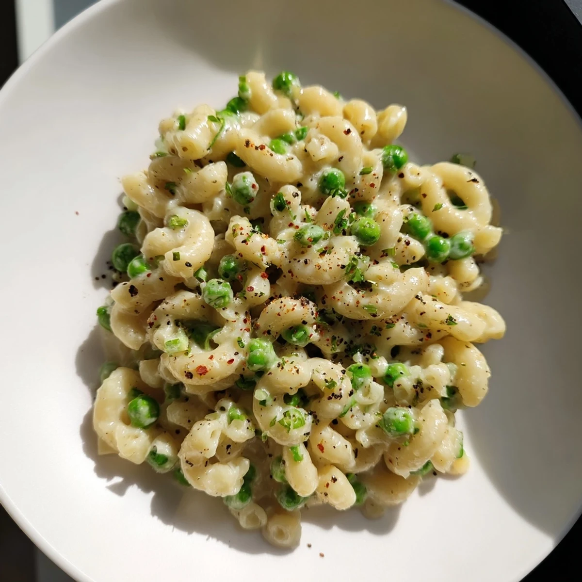 Close-up of golden macaroni and peas with fresh herbs, a simple weeknight classic.
