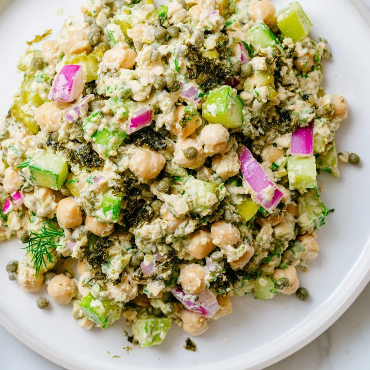 Creamy chickpea tuna salad, a vegan delight with chunks of celery and seaweed, ready to eat.