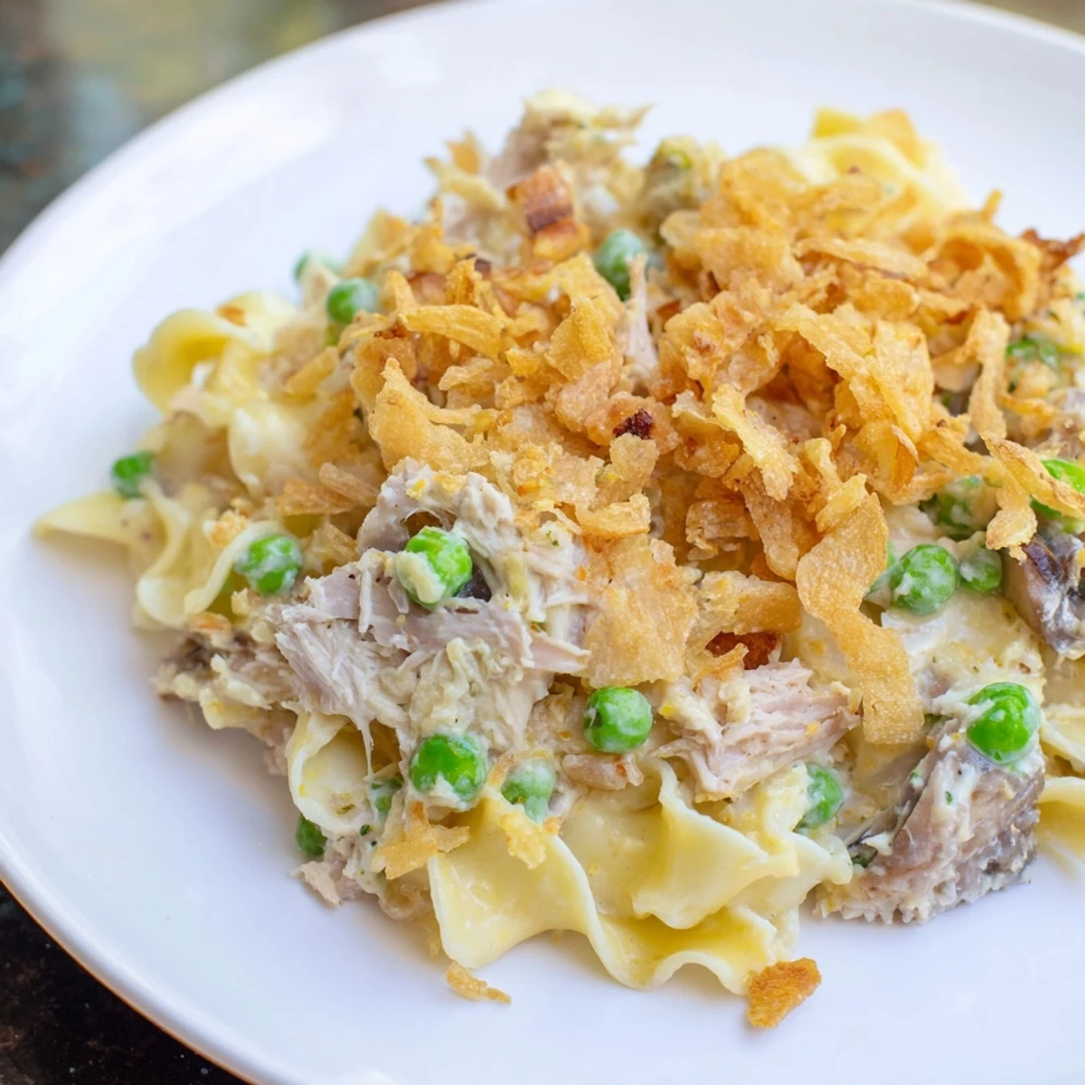 A bubbly tuna noodle casserole, topped with golden crispy onions, ready for a comforting meal.