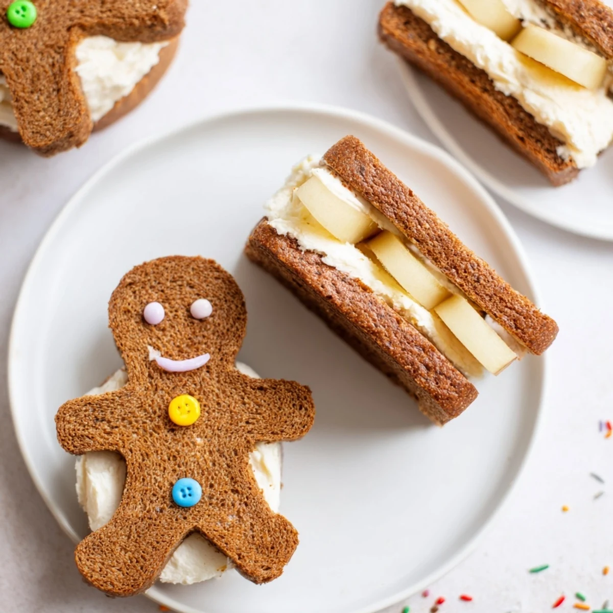 Sweet cream cheese filling flows from gingerbread man sandwich cutouts, topped with apple slices for a fun snack.