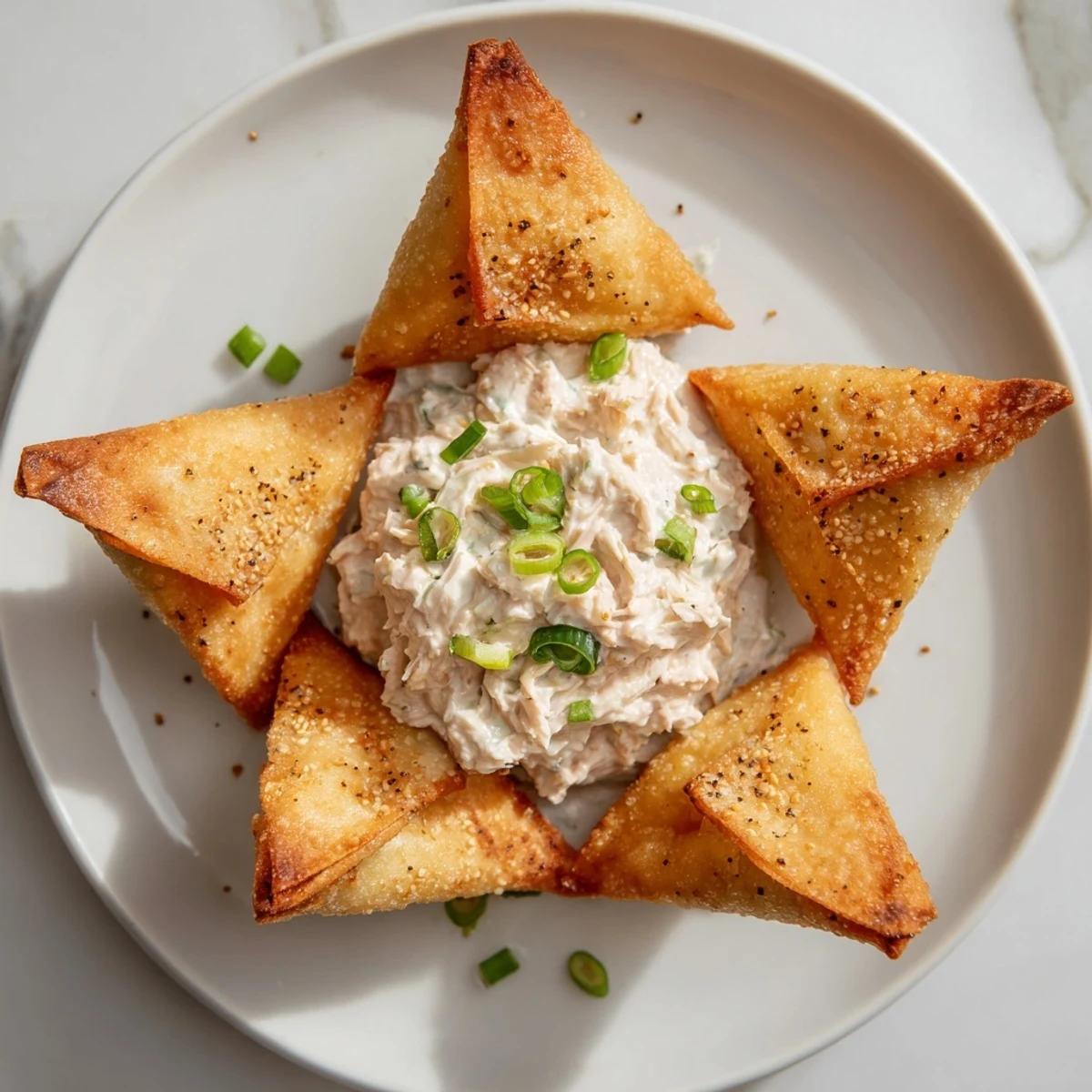 A close-up of crispy Air Fryer Lumpia Chips surrounded by a rich, creamy chicken dip ready to eat.