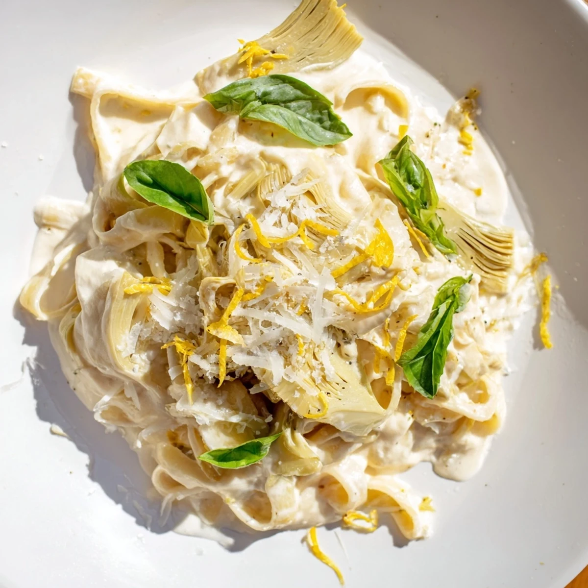 Bright, flavorful Creamy Lemon Artichoke Pasta, served with a dusting of Parmesan, showcasing delicious textures.