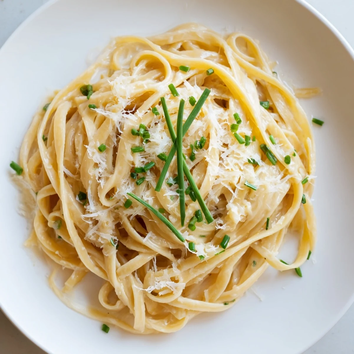 Steaming bowl of Miso Butter Pasta: creamy noodles coated in rich, umami sauce with fresh chives.