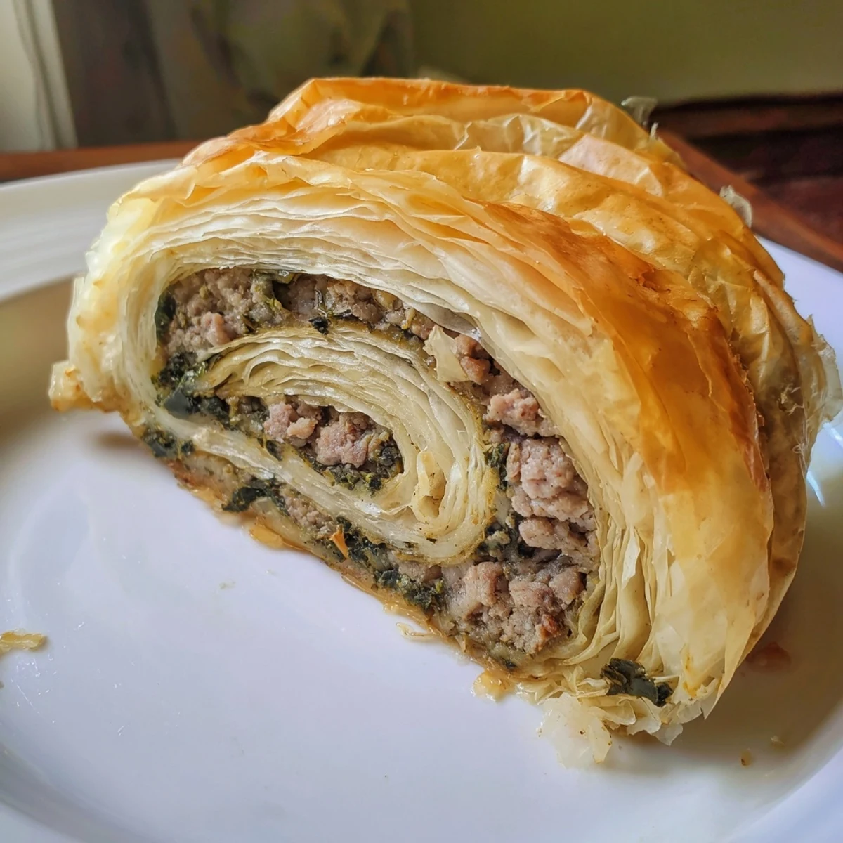 Golden-brown Bosnian Burek pastry: flaky phyllo layers filled with savory ground beef and spinach.