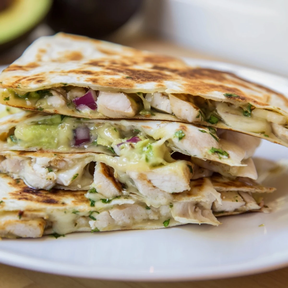 Crispy tortilla holding a flavorful Chicken Avocado Quesadilla, ready to eat with melted cheese.