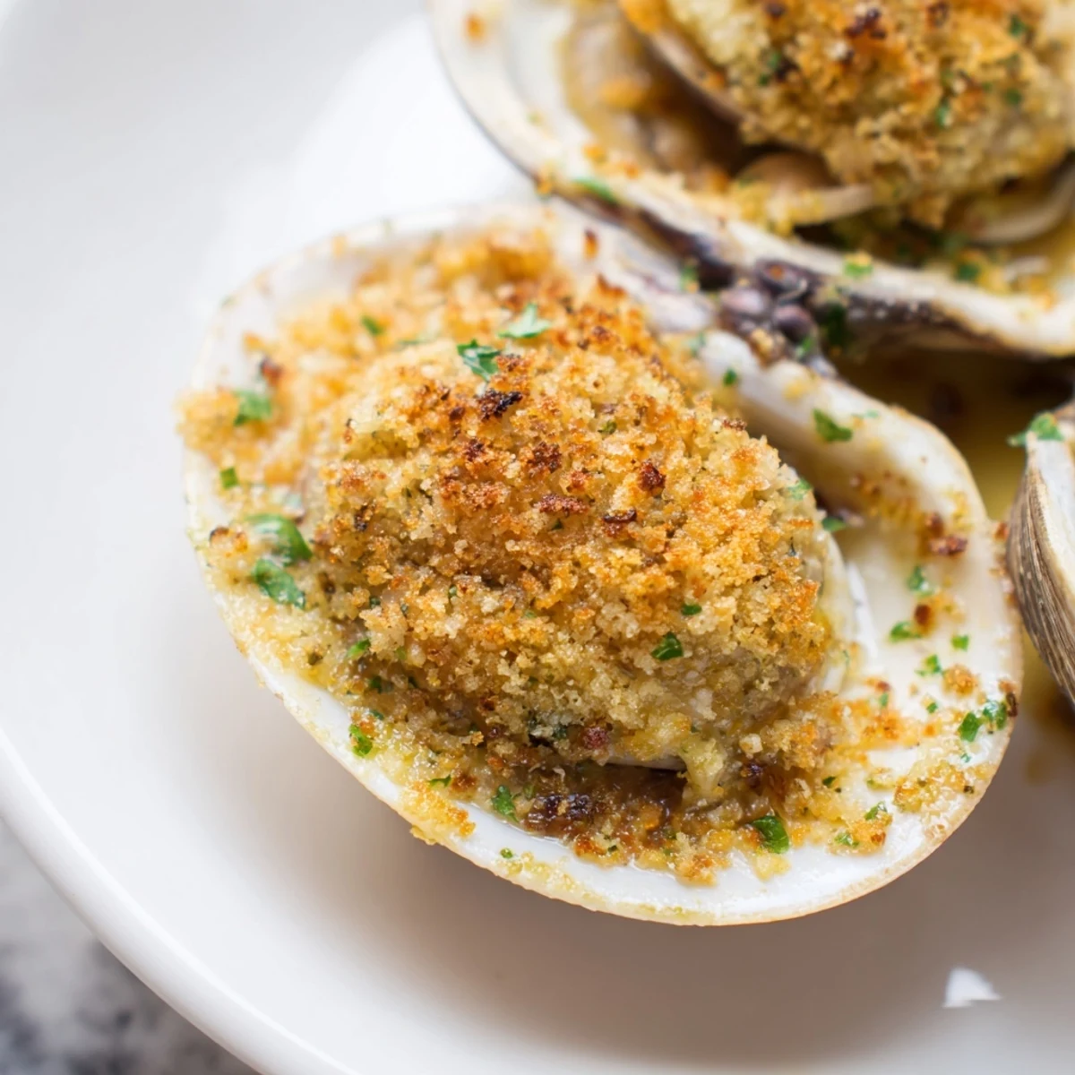 Golden roasted clams with lemony panko topping, arranged on a baking sheet with fresh parsley and lemon wedges.