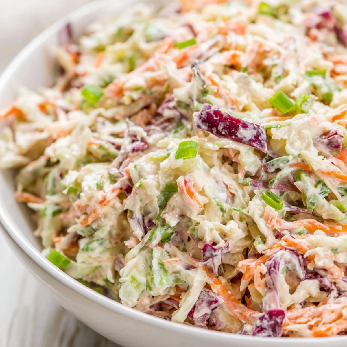 A bowl of Best Cabbage Coleslaw with vibrant orange carrots, paired with grilled pulled pork and a cold lemonade.