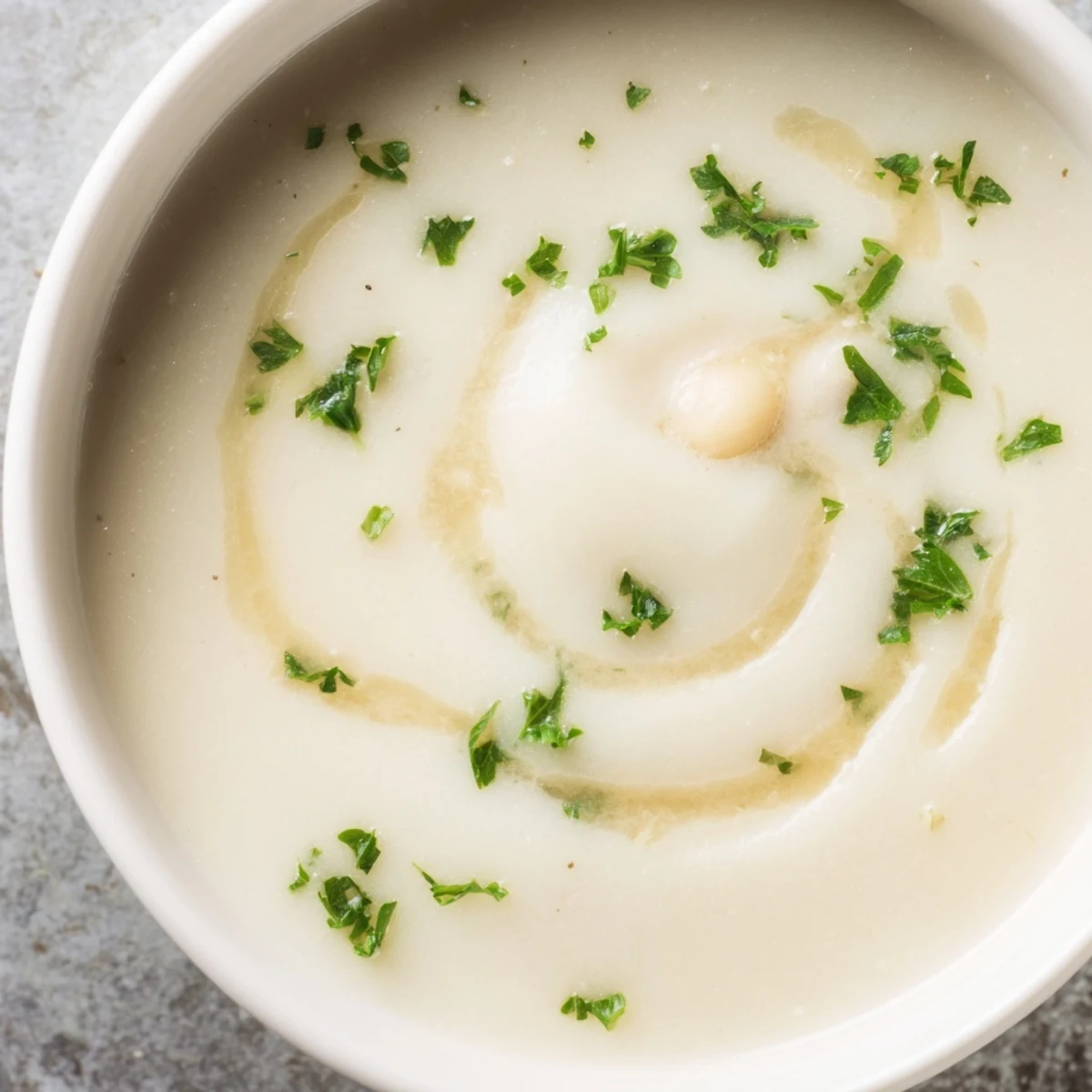 Steaming white bean and Parmesan soup served with crusty bread on a wooden table for dipping.