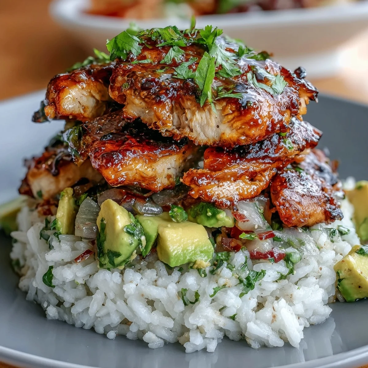 A vibrant stack of Tangy Honey Lime Chicken with fluffy jasmine rice and creamy avocado salsa, garnished with a fresh lime wedge.