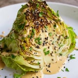 A close-up of tender roasted cabbage wedges drizzled with creamy tahini sauce and sprinkled with sesame seeds.