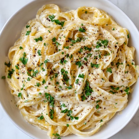 A bowl of pasta with green herbs on top.
