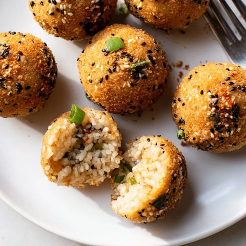 Golden brown Japanese sesame-fried rice balls: crispy, savory snack served warm.