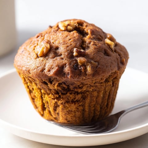 Golden brown Ginger-Spiced Pumpkin Muffins cooling on a wire rack, spiced and fragrant.