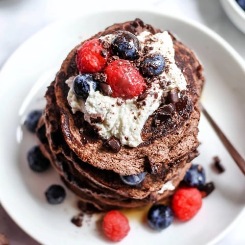 Fluffy Protein Chocolate Ricotta Pancakes stacked high, drizzled with syrup and fresh berries.  
