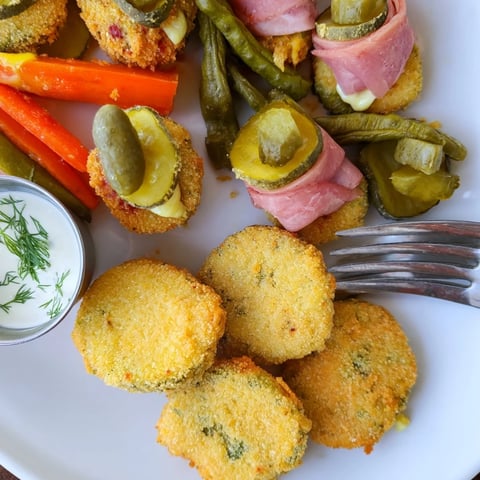 Crispy fried pickles served with tangy ranch dipping sauce on a platter.  