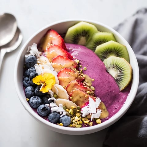 Vibrant smoothie bowls with pistachio and purple yam topped with fresh fruits.