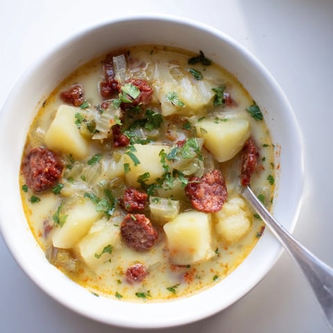 Creamy Potato, Leek & Chorizo soup garnished with fresh parsley and crusty bread.  