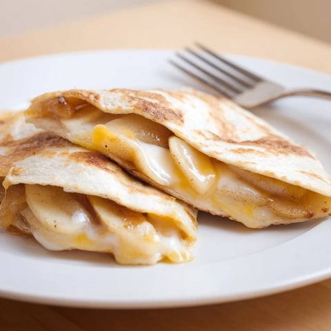 Golden caramelized apple and cheddar quesadillas, crispy and cheesy perfection on a plate.  