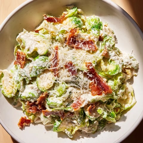 Warm Brussels Sprouts Caesar salad, featuring crispy prosciutto and Parmesan, garnished and ready to eat.