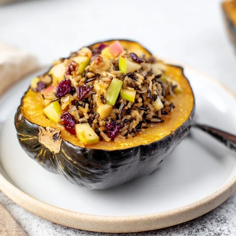 Golden-brown stuffed acorn squash with maple sriracha drizzle, inviting flavors from a hearty vegetarian dish.