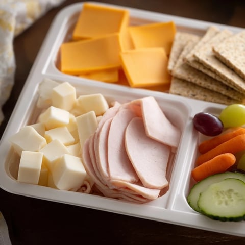 DIY Lunchables tray with sliced turkey, cheese, crackers, and grapes, a ready-to-eat kids lunch.