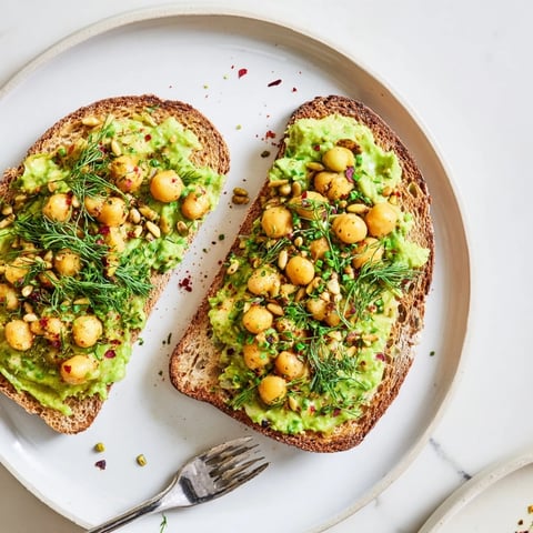 Crispy toasted bread topped with creamy avocado toast and sprinkled with fresh herbs.