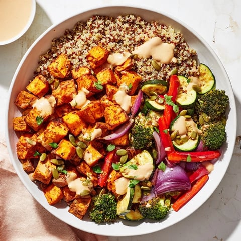 Quinoa bowl with roasted veggies, vibrant colors and drizzle of lemon-tahini dressing, a healthy meal.