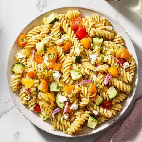 Vibrant pasta salad with seasonal veggies, tossed in a bright, zesty dressing, ready to eat.