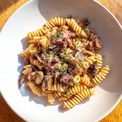 Fusilli with Bacon, Onions, and Mushrooms: A steaming bowl of pasta, showcasing crispy bacon and sautéed mushrooms.