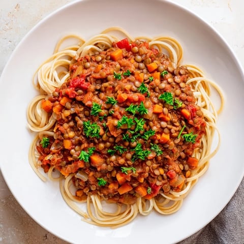 Steaming bowl of Hearty Lentil Bolognese, a hearty vegan classic served over spaghetti.