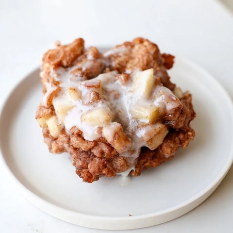 Golden-brown homemade apple fritters, crispy outside, served warm with sweet vanilla glaze.