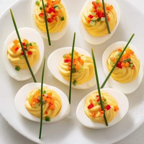 Easy festive deviled egg ornaments, vibrant with red and green pepper bits, ready for the holiday table.