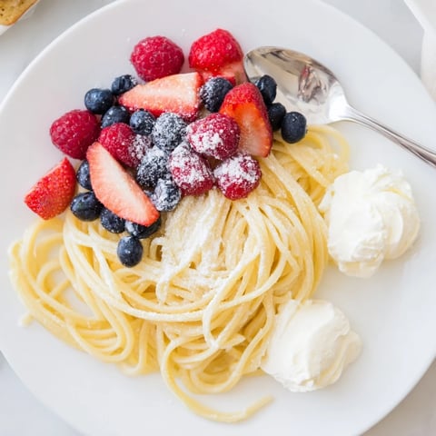 Quick Festive Pancake Spaghetti, a whimsical brunch dish with fresh berries and powdered sugar.
