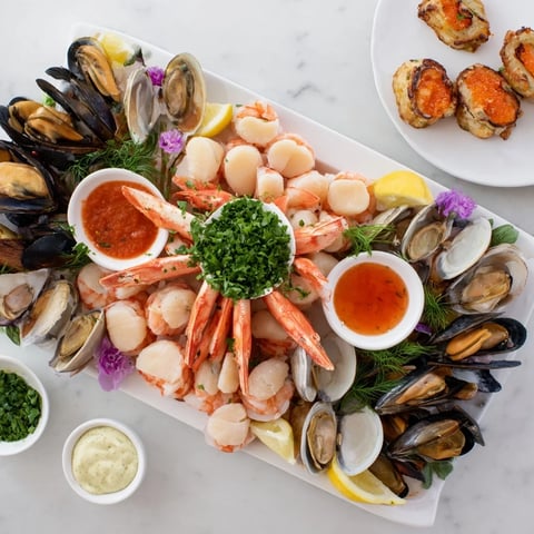 Behold the elegant Starfish & Shell Appetizer Board, brimming with fresh seafood and zesty sauces, ready to eat.