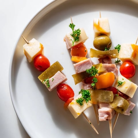 Savory Skewers appetizer: a close-up of colorful meat, cheese, and pickle cubes on skewers.