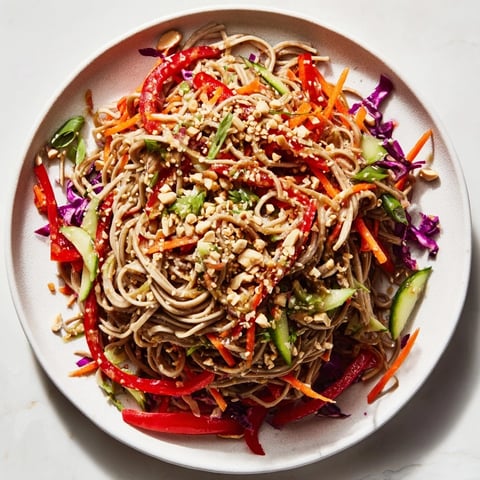 A vibrant Cold Noodle Salad with Sesame-Ginger Dressing, tossed and ready to serve with peanuts.