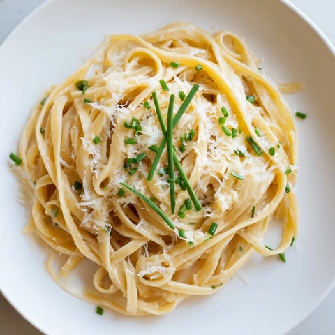 Steaming bowl of Miso Butter Pasta: creamy noodles coated in rich, umami sauce with fresh chives.