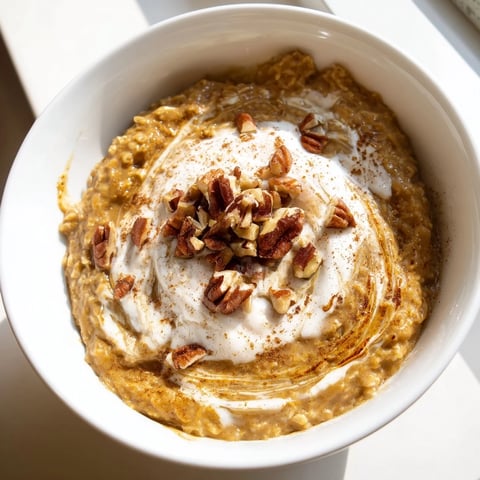 Steaming bowl of pumpkin spice latte oats with a swirl of whipped cream and a cinnamon sprinkle.