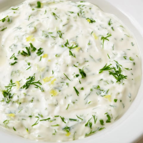 Fresh Greek Yogurt Herb Dip drizzled on a platter, ready with colorful vegetables for dipping.