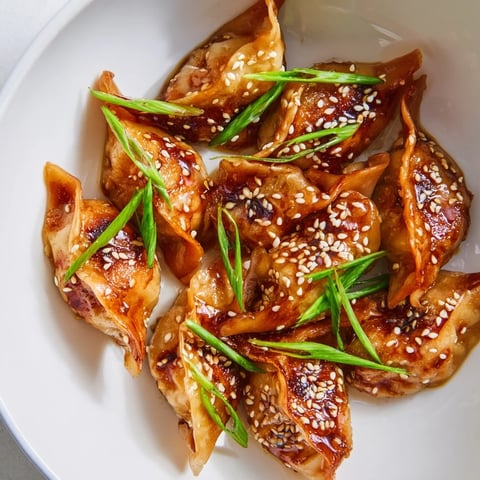 Crispy, golden air fryer frozen dumplings glistening under a sesame oil glaze, a delicious snack.