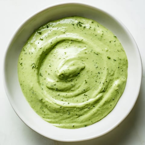Bright green Green Goddess Dressing swirled in a glass jar, ready to pour over a fresh salad.