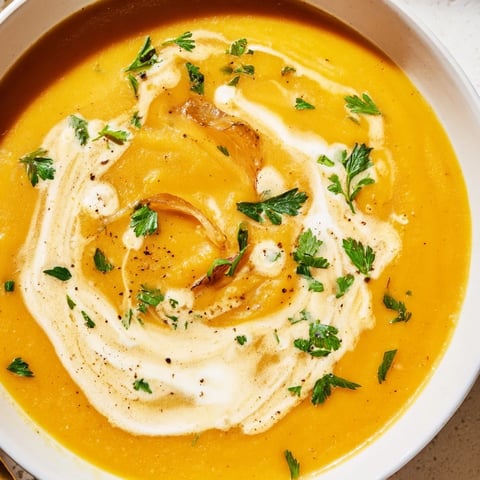 Golden carrot-based creamy soup, a vibrant orange hue, ready to be ladled into bowls.
