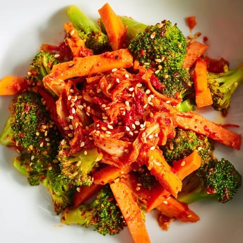 A vibrant bowl of Comforting Fermented Veggie Winter Stir-Fry features crisp broccoli, carrots, and sweet potato tossed with spicy kimchi and sesame seeds.  