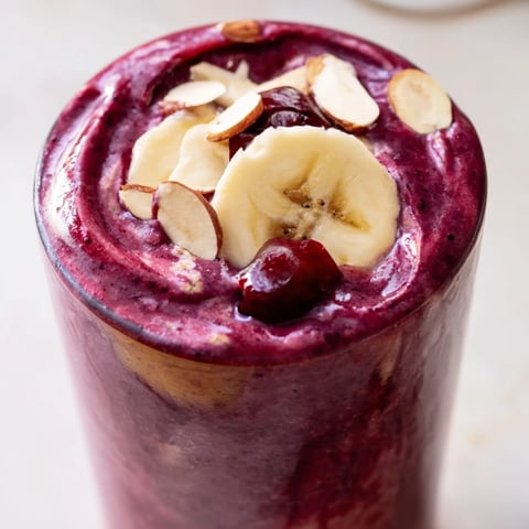 Two frosted glasses of Cherry Almond Smoothie, garnished with sliced almonds and a few fresh cherries, perfect for a refreshing breakfast.