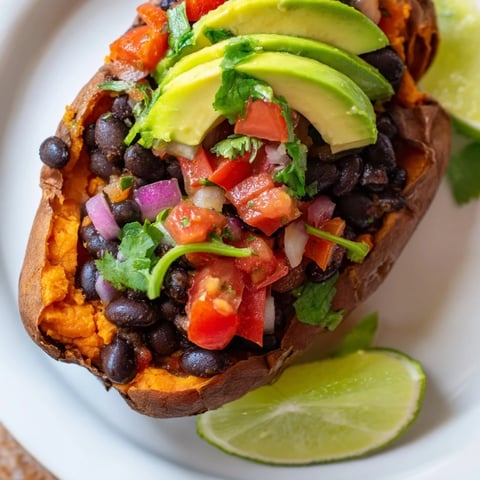 Roasted Sweet Potatoes With Chipotle Black Beans and Zesty Tomato Salsa served in the roasted skins, topped with creamy avocado and fresh cilantro for a vibrant, hearty meal.