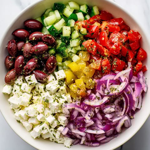 A bowl of Greek salad with a lemon vinaigrette dressing.