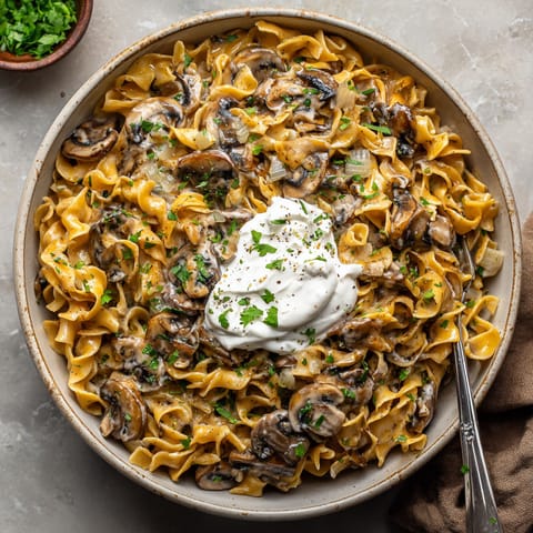 A bowl of pasta with mushrooms and white sauce.